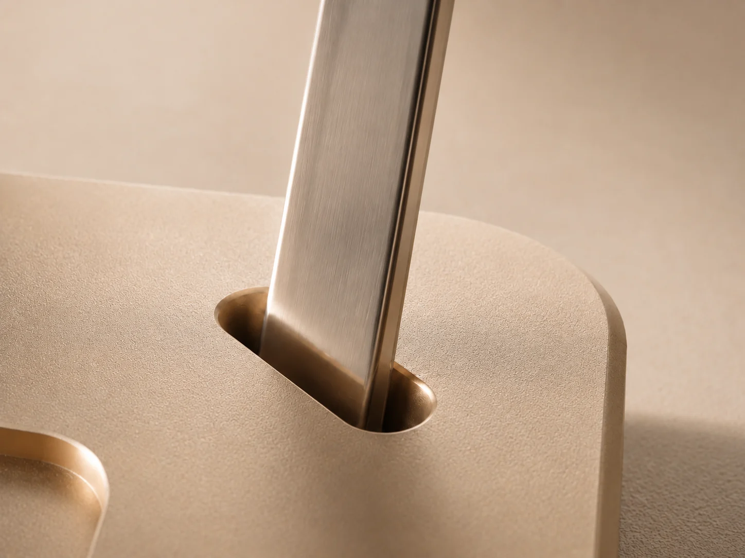 Polished steel spoon standing upright in the integrated dock of the NOÉ saucer